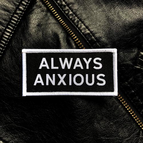 "Always Anxious" in white block text embroidered on black patch with white merrowed edge.  Art by Print Ritual.