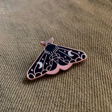 Black enamel pin of luna style moth with white moons and gold accents. Glossy finish.
